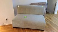 Front view of a light green-gray love seat showing the backrest and seat cushion with visible spots and stains on fabric.