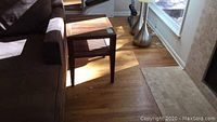 Two teak-like wood end tables positioned next to a sofa on wood flooring, showing the design and scale of the tables.