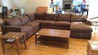 Angled front view of brown suede sectional showing left-arm, middle, right-arm modules and chaise lounge