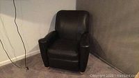 Front view of black leather recliner chair showing cushioned seat, armrests, and backrest.