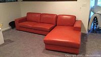Full view of red leather sectional sofa and chaise in carpeted basement room