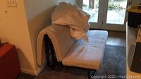 Side view of metal futon sleeper in sofa configuration with mattress and cover, showing wear and stains on mattress.