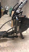 Side view of elliptical showing frame, flywheel cover and foot pedals