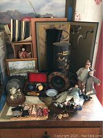 Overview of Asian decorative lot including dolls, figurines, framed art, and ceramic stress balls