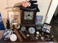Full lot showing all items including vintage clock, oil lamp, decorative figurines, pocket watches, compasses, and other small collectibles arranged on a table.