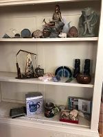Front view of shelf with various decorative items: agate coaster set, agate slices, rock specimens, oil rig music box figurine, stone candleholders, and mugs.