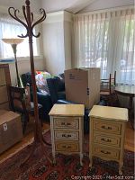 Photo of the two vintage bedside tables and tall wooden coat rack in room with natural lighting.