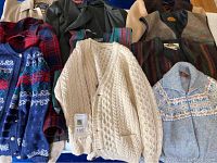 Nine wool garments—sweaters, vests and jackets—laid out on table