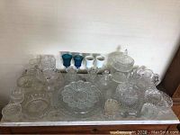 Full overview of all the vintage crystal items on a marble surface including candelabras, bowls, decanter, platter and small dishes