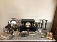 Wide view of the lot displaying vintage mantel clock, silver plated items and Limoges porcelain pieces arranged on marble surface