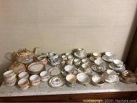 Full lot of assorted tea service pieces displayed on marble surface