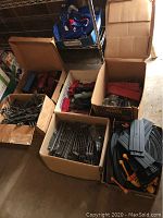 Overview of four boxes containing vintage toy trains, metal train tracks and accessories