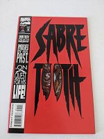 Front cover showing bright red background and black Sabretooth title with face graphic behind title text
