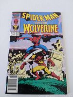 Front cover of Spiderman versus Wolverine comic book showing the title and artwork of Spiderman fighting Wolverine in a graveyard scene.