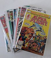 Stack of Alpha Flight comic books in protective plastic sleeves showing colorful cover art from Marvel Comics Group, including issue #1 prominently in front.