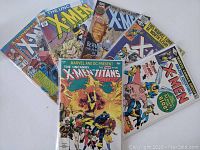 Photo showing full set of 8 comic books from the lot including Uncanny X-Men and New Teen Titans issues.