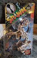 Front view of sealed 1996 Spawn Series 7 Scourge figure in original blister card packaging showing figure details and card graphics.
