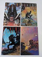 Four Aliens Genocide comic books issues 1 to 4 arranged in two rows showing front covers with alien figures and atmospheric scenes.