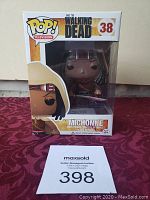 Funko Pop! Television Michonne #38 in original packaging displayed on a red patterned surface.