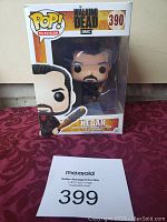 Funko Pop! Television Negan #390 vinyl figure in original window box packaging on red patterned fabric background.