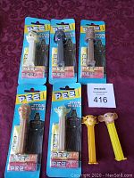 Photo showing five unopened Star Wars PEZ dispensers and two opened Lion King PEZ dispensers on a maroon fabric background.
