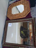 Photo showing two mirrors, one with a woven wood octagonal frame and the other with a brown rectangular frame with gold trim.