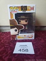 Funko Pop Carl Grimes The Walking Dead figure number 388 in original box on red surface with auction number card.