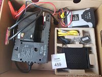 Photo of electrical lot including APC UPS, digital multimeter, cables, and network hardware.