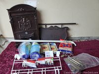 Photo showing all household items including mailbox, door rack, curtain rod, vacuum filters, wall plug covers, and brass handles on a maroon fabric