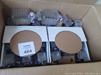 Top-down photo of 22 glass liquid decanters with clear glass stoppers inside a cardboard shipping box, separated by cardboard partitions