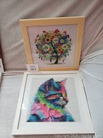 Two framed diamond paintings: one of a colorful tree and one of a vibrant cat profile, displayed side by side.