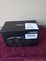 Photo of VR Shinecon virtual reality headset in original black box on a purple surface