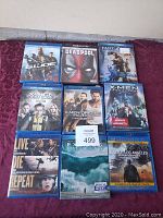 9 Blu Ray movies laid out on purple fabric background, showing clear titles and cover images.