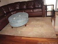 Full view of wool area rug placed on wooden floor with furniture around showing the pattern and condition of the rug.