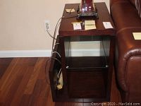 Photo of one solid wood end table showing single glass shelf and side magazine rack from above and side angle.