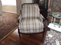 Front view of the arm chair showing wood frame and striped loose cushion seat and pillow back.