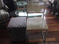 Kitchen chair and fabric covered stool side by side showing sizes and styles, chair is metal framed with plastic caning seat and back, stool is fabric covered with swirl pattern.