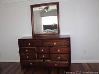 Front view of dresser with mirror mounted above it, showing drawer layout and knobs.