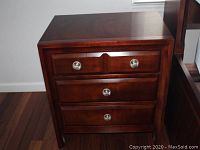 Front view of three-drawer wooden nightstand with matte silver round knobs and dovetailed drawer joints.