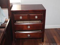 Front view of the wooden nightstand with three drawers partially open, showing the dovetail construction inside drawers and matte silver round knobs on each drawer.