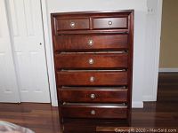 Front view of six-drawer dresser showing dark wood finish and matte silver knob hardware