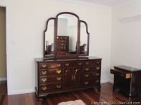 Full view of dresser with attached three-panel mirror in wooden frame, showing overall style and condition.