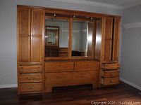 Full front view of Thomasville solid wood wall unit with multiple drawers, doors, and mirrored center section