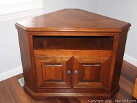 Wooden corner entertainment stand showing front view with open shelf and closed double doors below.