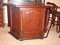 Front and angled views of the wooden bar front showing twisted fluted columns and metal footrest pipe.