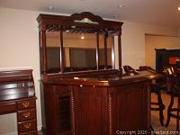 Photo showing full bar back with dark wood finish, twisted fluted columns, and three-panel mirror back