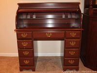 Front view of roll top desk showing open roll top with cubbies and all drawers closed