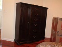 Front view of dark wood triple armoire dresser showing six drawers and two cabinet doors.