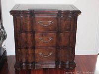 Front view of the small dresser showing the curved drawer fronts and brass-tone handles.