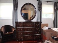Full front view of the dresser with the round mirror hung above it, showing brass hardware and dark wood finish.